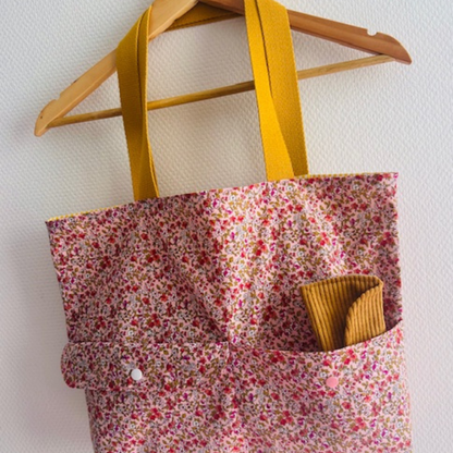 Détail des finitions couture des poches avant du sac en coton fleuri rose.